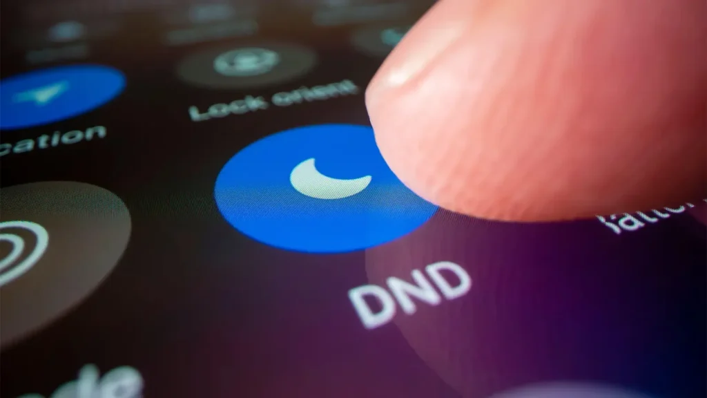 a person's finger tapping on a smartphone screen to select the "Do Not Disturb" (DND) mode