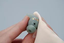  a Sony LinkBuds Fit earbud being cleaned with a cloth